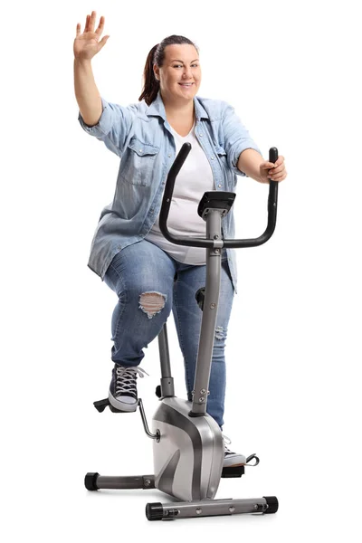 エアロバイクの運動の分離の白い背景を振って太りすぎの女性の完全な長さの肖像画 — ストック写真
