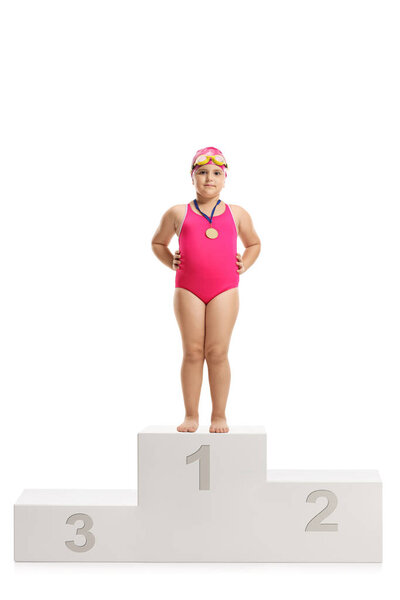 Little girl swimmer with a gold medal standing on a winner's podium isolated on white background