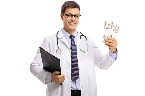 クリップボード 白い背景で隔離のお金の束を持つ医師 — ストック写真