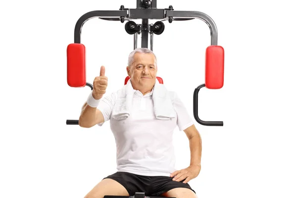 Mature Man Seated Exercise Machine Holding His Thumb Isolated White — Stock Photo, Image