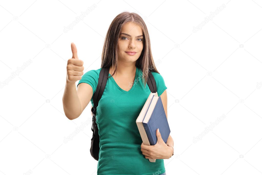 Beautiful female student with a backpack and books showing thumbs up isolated on white background