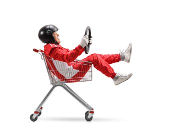 Elderly man in a racing suit with helmet holding a steering wheel and sitting inside a shopping cart isolated on white background clipart