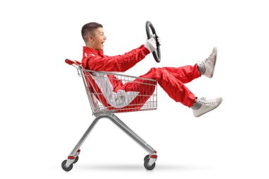 Teenage boy in a racing suit holding a steering wheel and sitting inside a shopping cart isolated on white background clipart