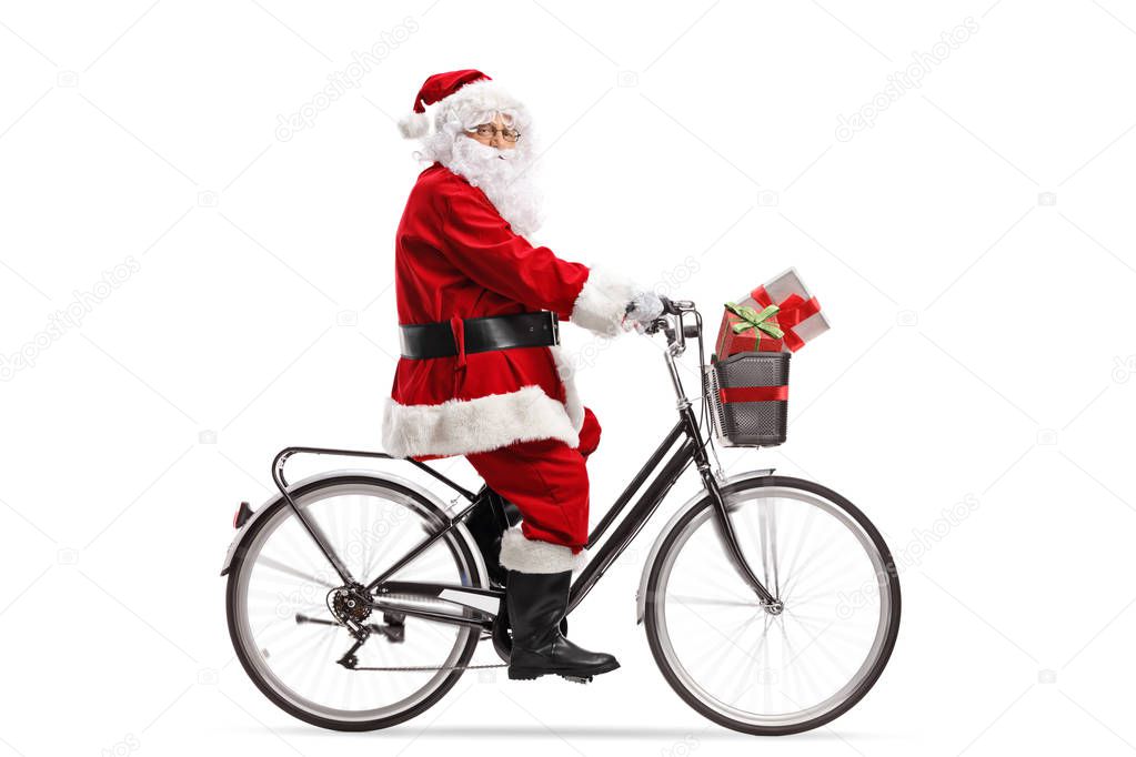 Full length profile shot of Santa Claus riding a bicycle isolated on white background