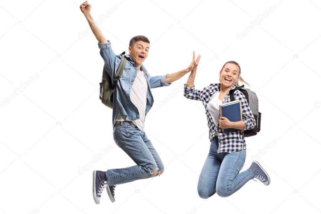 Full length portrait of a two overjoyed teenage students in mid-air high-fiving each other isolated on white background