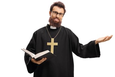 Young priest holding an open bible and gesturing with hand isolated on white background clipart