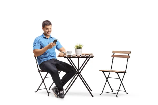 コーヒー テーブルに座っていると 白い背景で隔離の携帯電話を探して若い男 — ストック写真