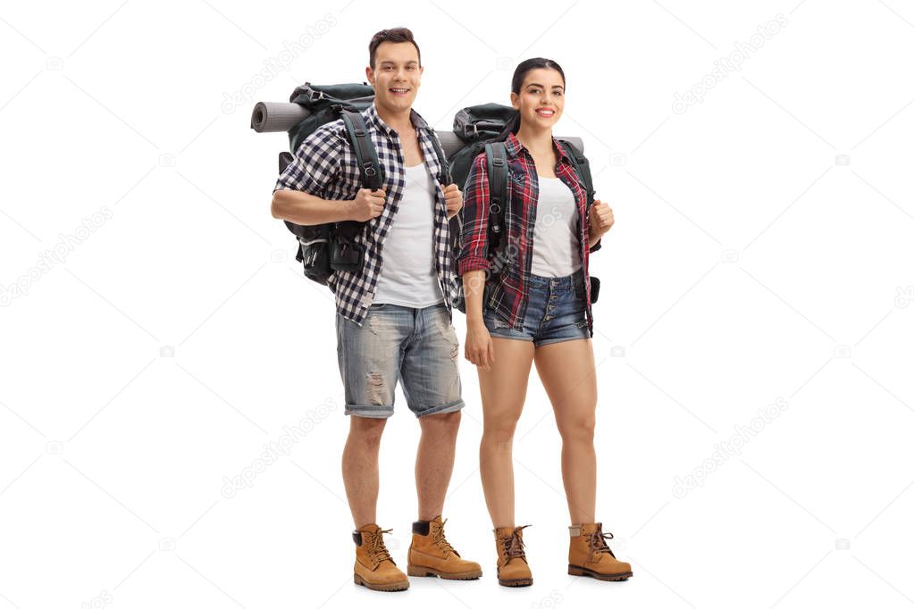 Full length portrait of male and female hikers with backpacks standing and looking at the camera isolated on white background