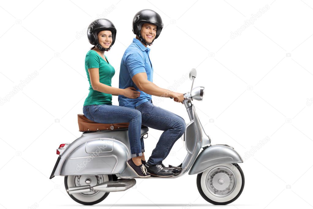 Full length profile shot of young male and female riding on a vintage motorbike and wearing helmets isolated on white background