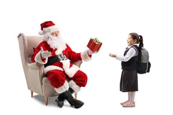 圣诞老人坐在扶手椅上 送给一个在白色背景上被隔离的惊讶的小女孩 送礼物 — 图库照片