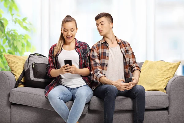 Adolescente Espreitando Telefone Uma Adolescente Sentada Lado Dele Sofá — Fotografia de Stock