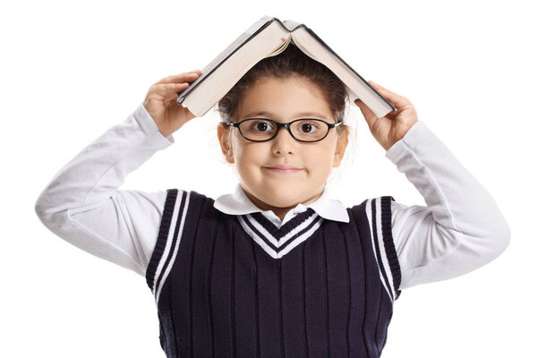 Little schoolgirl holding a book above her head isolated on white background