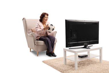 Bir koltuk futbol topu ile oturan ve beyaz arka plan üzerinde izole televizyonda maç izlerken yaşlı kadın