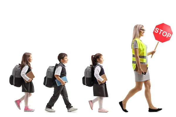 安全ベスト 白い背景で隔離一時停止の標識で女教師の背後を歩いて小学生の完全な長さのプロファイル撮影 — ストック写真