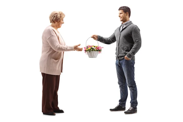 Full Length Shot Young Man Giving Abasket Flowers Elderly Woman — Stock Photo, Image