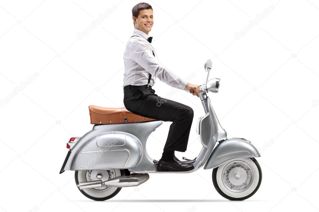 Full length shot of a young man in smart clothes riding a vintage scooter and looking at the camera isolated on white background