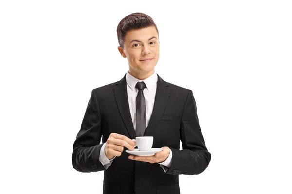 穿着西装的年轻人拿着浓咖啡杯 看着在白色背景上孤立的相机 — 图库照片