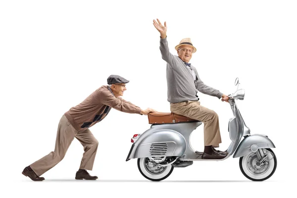 Senior Man Pushing Senior Gentleman Riding Vintage Scooter Waving Camera — Stock Photo, Image