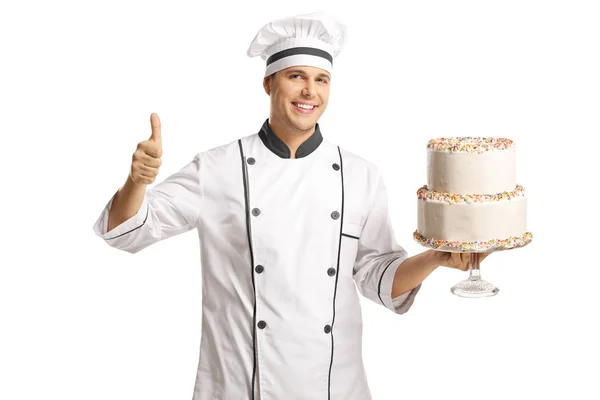 男厨师拿着两层蛋糕 并在白色背景上伸出大拇指 — 图库照片