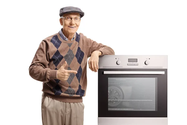 Senior Man Wijst Naar Een Elektrische Oven Geïsoleerd Witte Achtergrond — Stockfoto