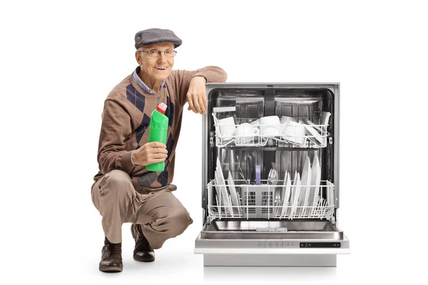 Senior Man Holding Detergent Kneeling Next Dishwasher Isolated White Background — Stock Photo, Image
