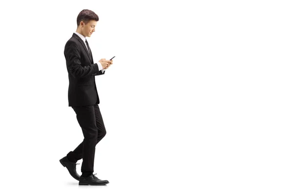 一个穿着黑色西装走路和打字的年轻人在白色背景上被隔离的手机的全长轮廓照片 — 图库照片