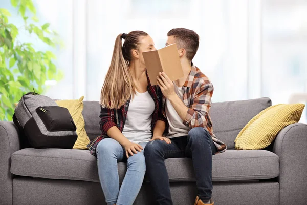Teenage Couple Kissing Sofa Hiding Book — Stock Photo, Image