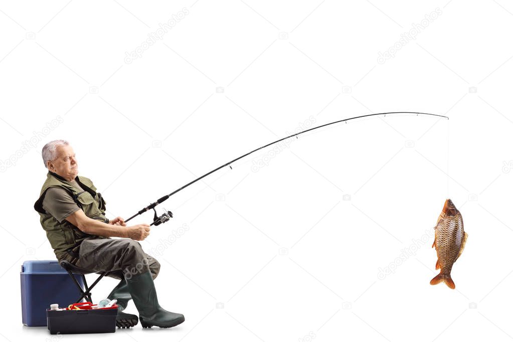 Full length shot of a fisherman with a big carp fish on the fishing rod isolated on white background