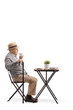 Baston oturan ve beyaz arka plan üzerinde izole kahve içme ile üst düzey bir adamın tam uzunlukta profil atış