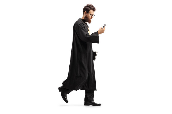 Full length shot of a priest walking with a mobile phone isolated on white background