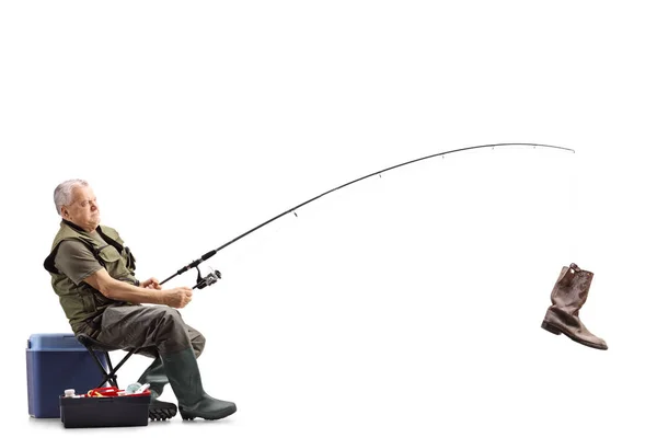 一个渔夫在椅子上的全长镜头 在白色背景上被隔离的钓鱼竿上放着一只旧靴子 — 图库照片