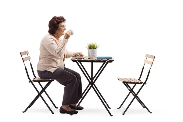 一位高级妇女在白色背景上隔离的桌子上喝咖啡的全长概况照片 — 图库照片