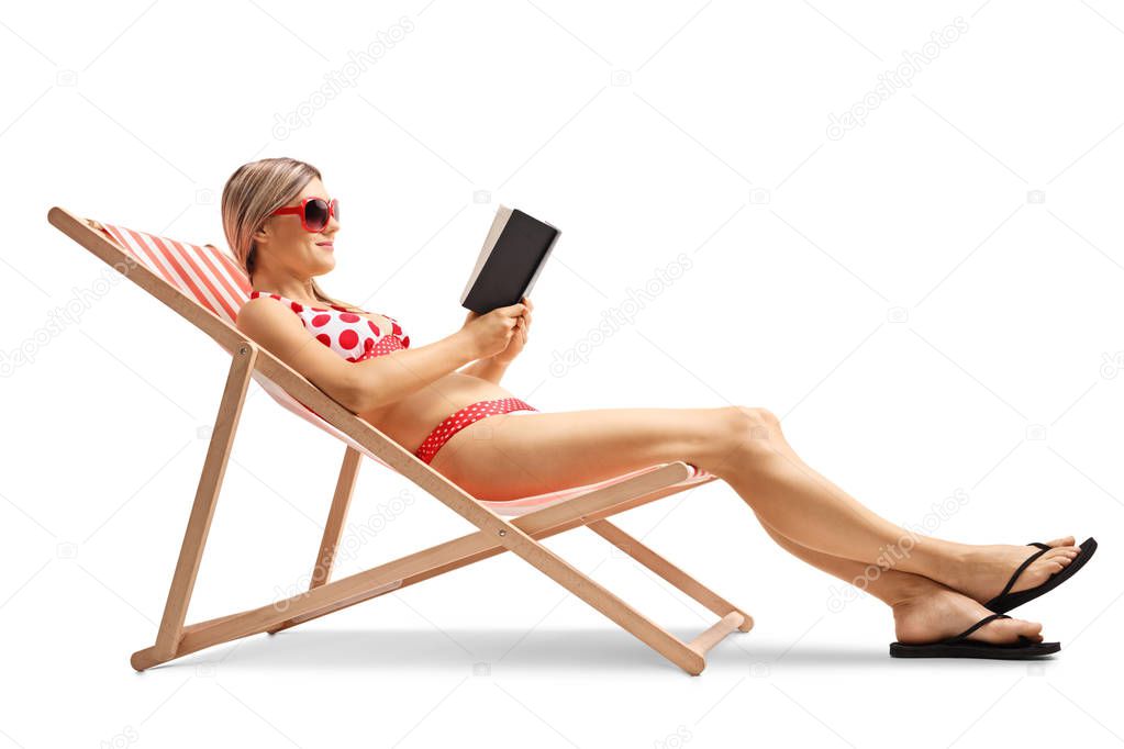 Young woman in a deck chair reading a book isolated on white background