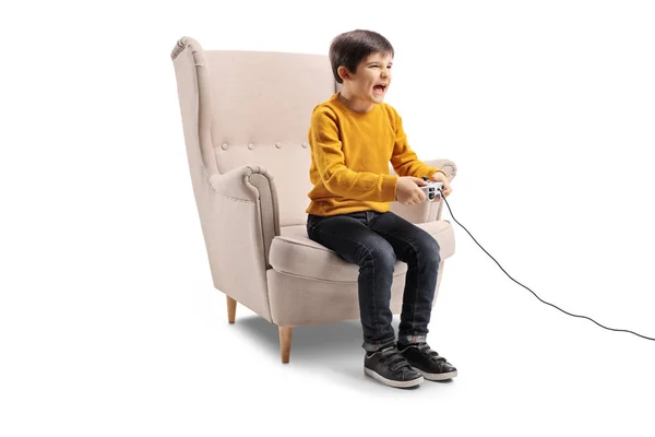 兴奋的孩子坐在扶手椅上 玩在白色背景上孤立的电子游戏 — 图库照片