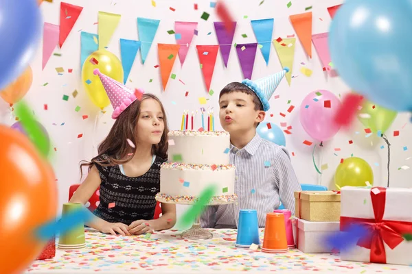 女の子とパーティーでケーキ誕生日から蝋燭を吹く少年 — ストック写真
