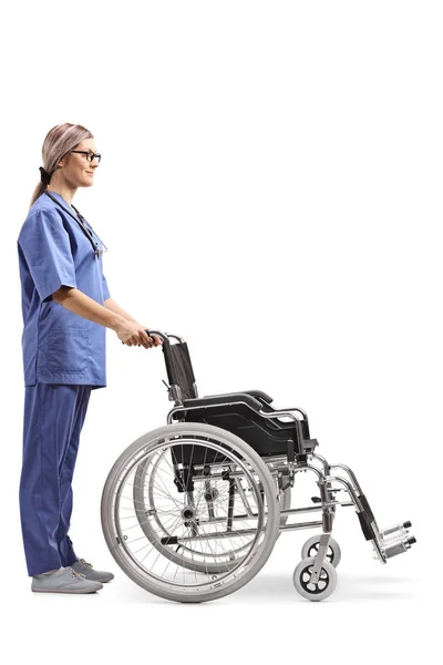 白い背景に分離された空の車椅子の若い女性看護師のフルの長さのプロファイル ショット — ストック写真