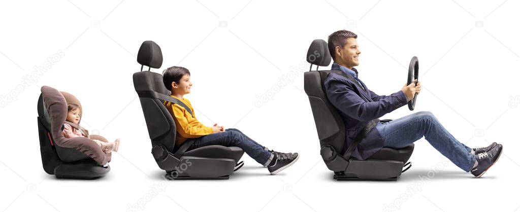 Full length profile shot of a father in a car seat holding a steering wheel with son and baby behind in car seats isolated on white background