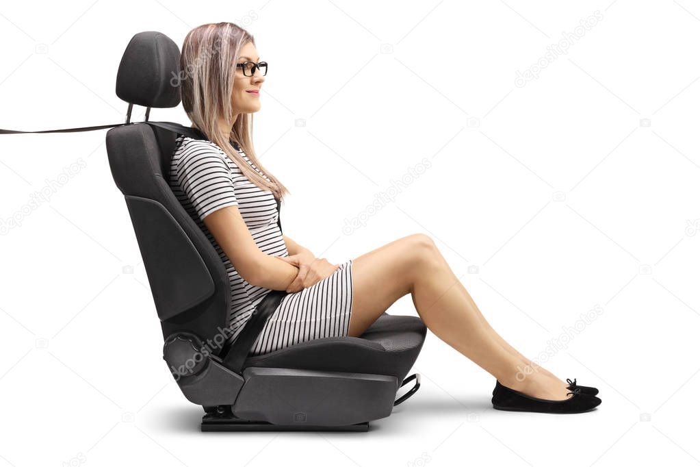 Full length profile shot of a young woman in a car seat with a fastened seat belt isolated on white background