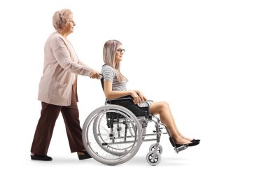 Genç bir kadın beyaz arka plan üzerinde izole tekerlekli sandalyede iterek yaşlı bir kadın, tam uzunlukta profil vurdu