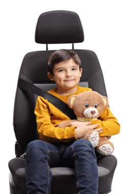 Boy in a car seat with a seat belt on holding a teddy bear isolated on white background clipart
