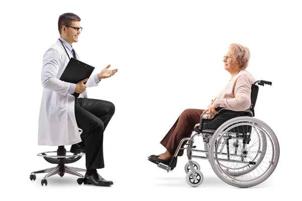 白い背景に分離された車椅子で成熟したメスの患者に話している男性医師の全身ショット — ストック写真