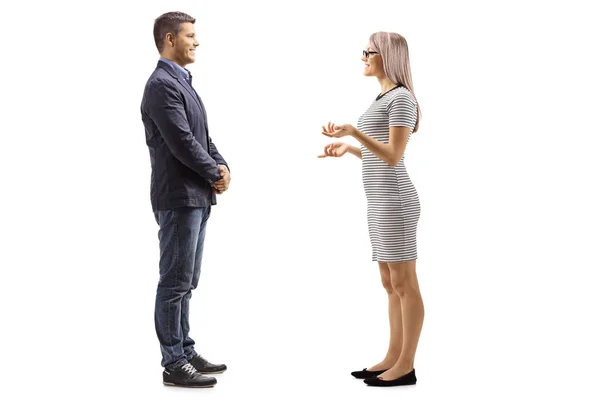 Full length profile shot of a young man and woman standing and having a con...