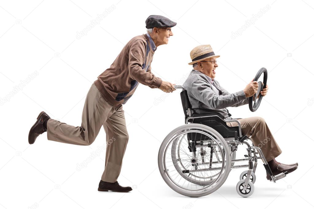 Full length profile shot of an elderly man pushing a man sitting in a wheelchair and holding a steering wheel from a car isolated on white background
