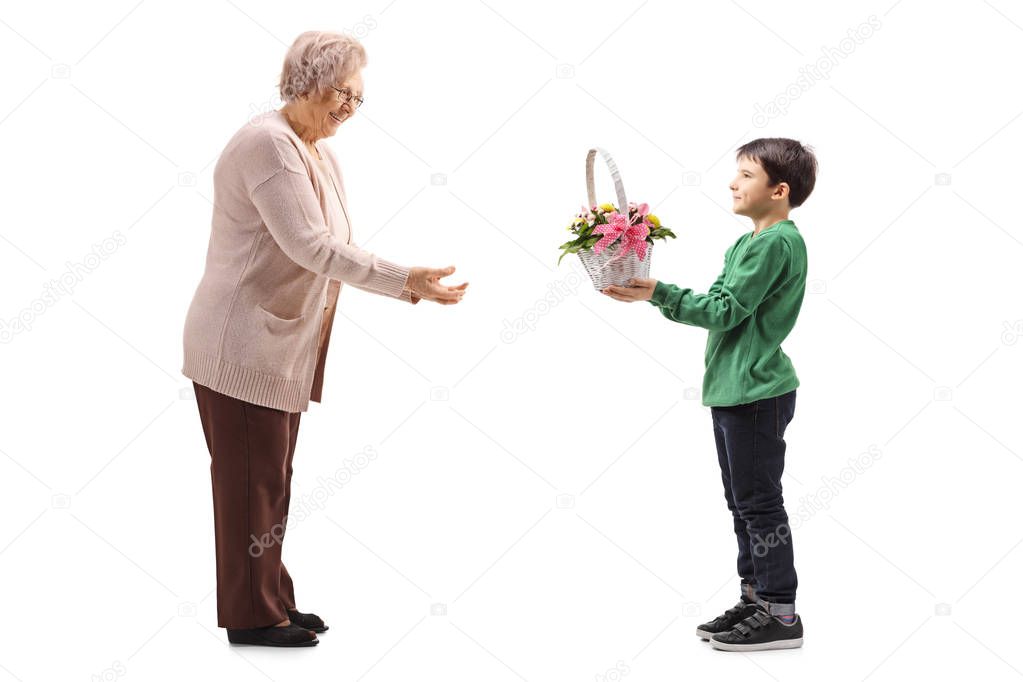 Full length profile shot of a grandson giving flowers to his grandmother isolated on white background