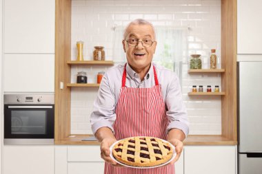 Bir taze pişmiş pasta tutarak ve bir mutfakta ayakta olgun adam