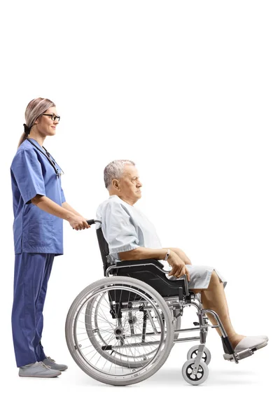 全長プロファイルショットを白い背景に分離された車椅子の高齢の男性患者を押す若い女性看護師の — ストック写真
