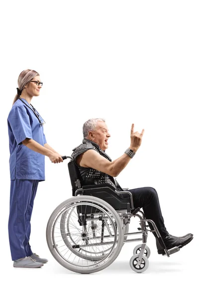 白い背景で隔離の車椅子サイン ロックン ロールをもうけて成熟した男性患者と若い看護婦さんの全身ショット — ストック写真
