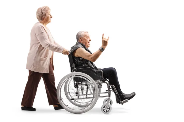 全长轮廓拍摄的一个老年妇女推一个成熟的男人做一个摇滚手的标志 在一个轮椅孤立的白色背景 — 图库照片