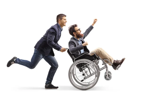 フルの長さを実行している若い男のショット 白い背景がある上に分離されて手でジェスチャー車椅子で興奮して男を押す — ストック写真