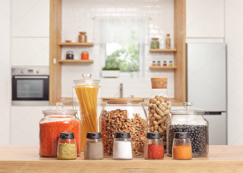 Many glass jars with different ingredients and spices on a kitchen worktop 